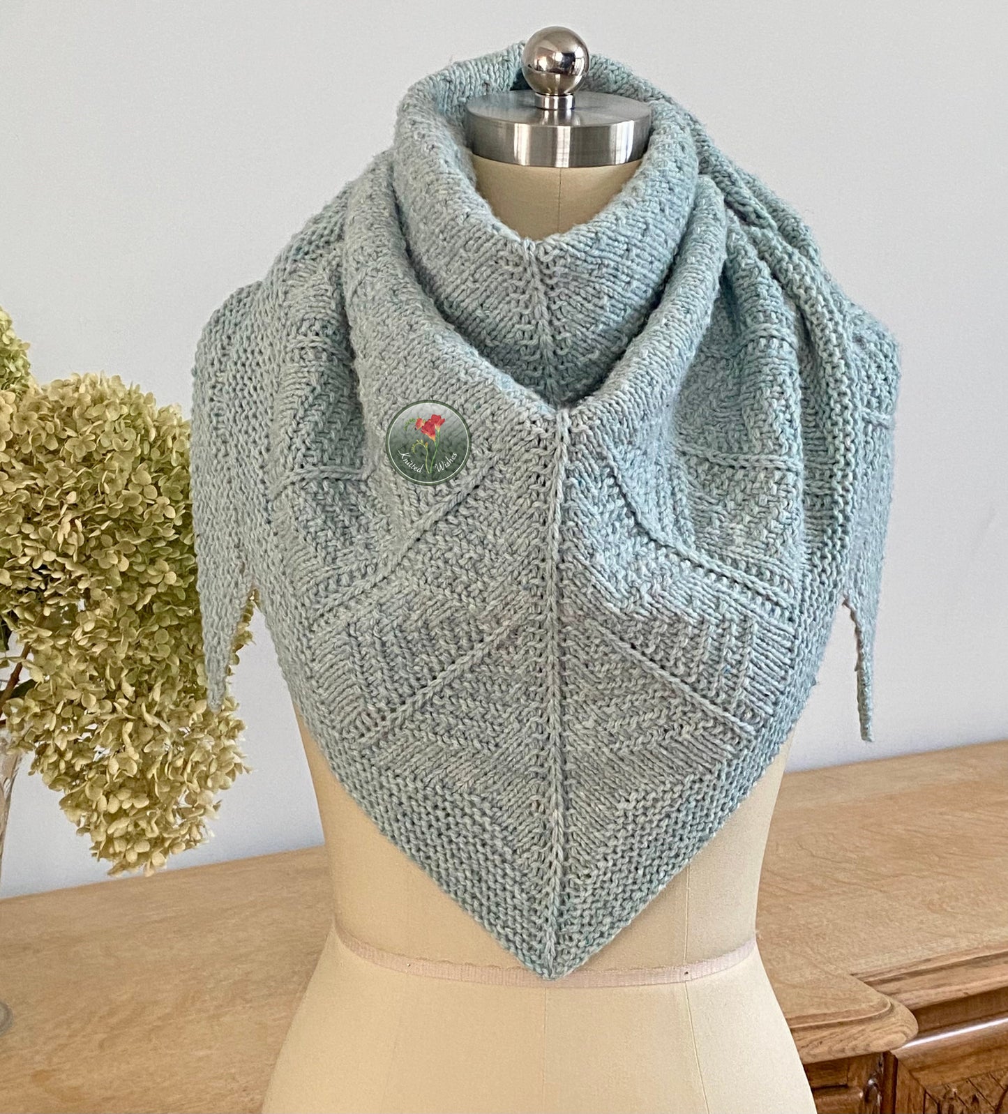 Knitted shawl with a tree pattern on a mannequin against a neutral background