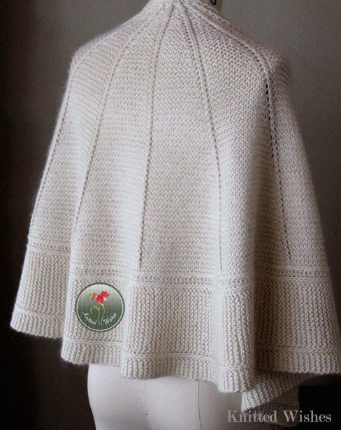 Knitted textured cream shawl on a mannequin against a dark background.