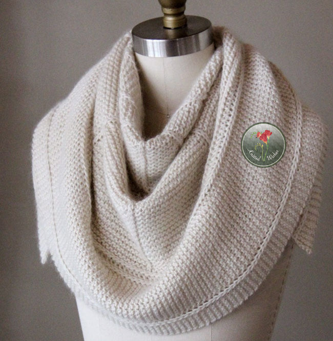Knitted cream textured shawl on a mannequin with against a neutral background