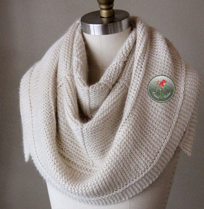 Knitted cream textured shawl on a mannequin with against a neutral background