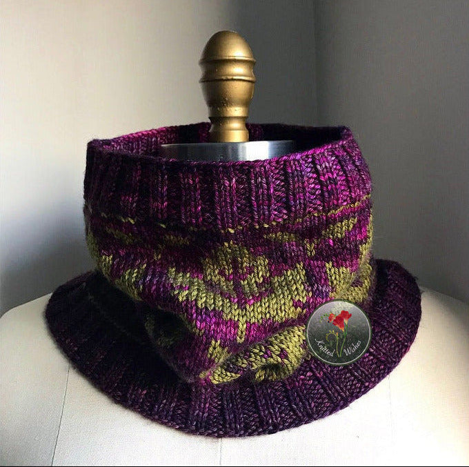 Knitted cowl with purple and green maple leaf pattern on a mannequin against a neutral background