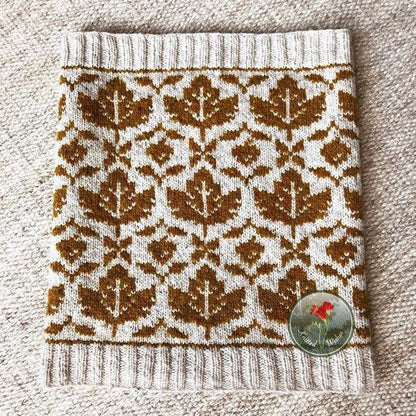Knitted stranded colorwork cowl with a maple leaf pattern on a textured surface