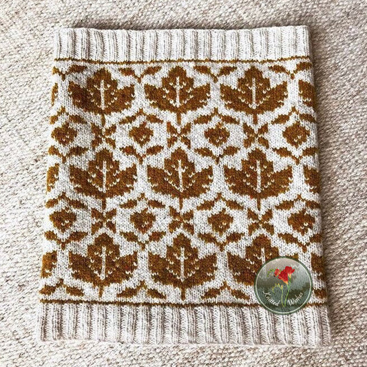 Knitted stranded colorwork cowl with a maple leaf pattern on a textured surface