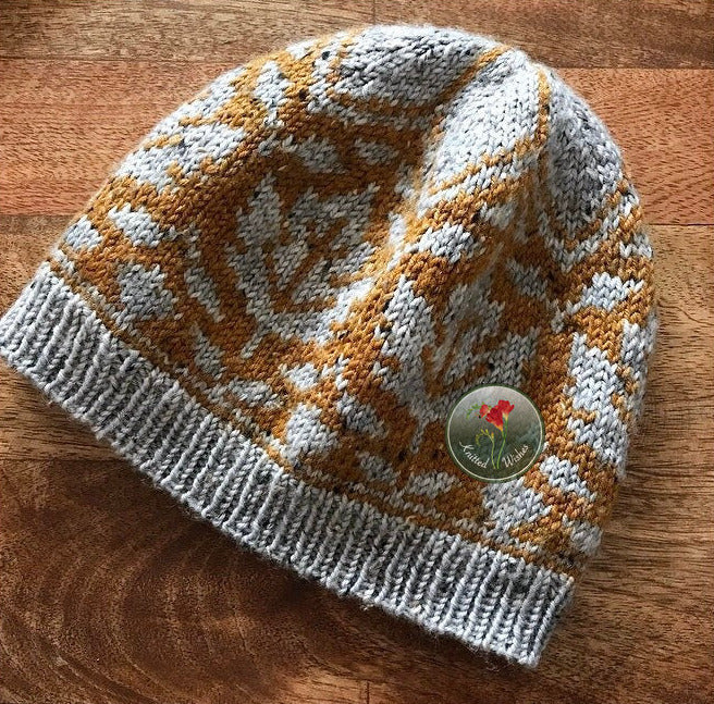 Knitted beanie with a maple leaf and acorn  pattern and on a wooden surface