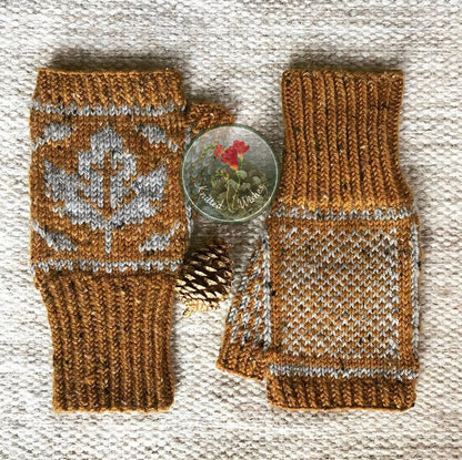 Pair of knitted fingerless mitts with a maple leaf pattern on a textured surface.