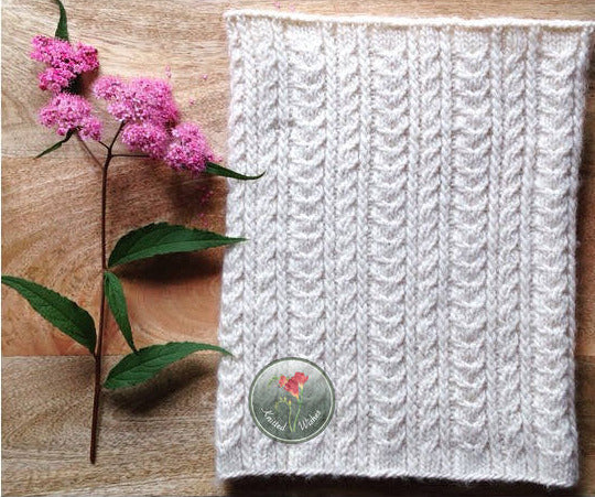 White knitted cowl and a flower on a wooden surface