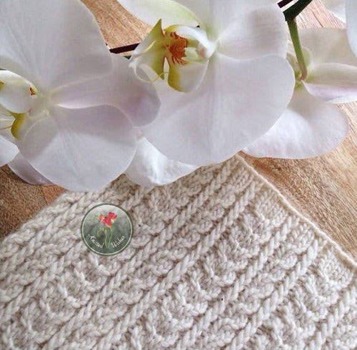 Knitted textured cowl and white orchids on a wooden surface