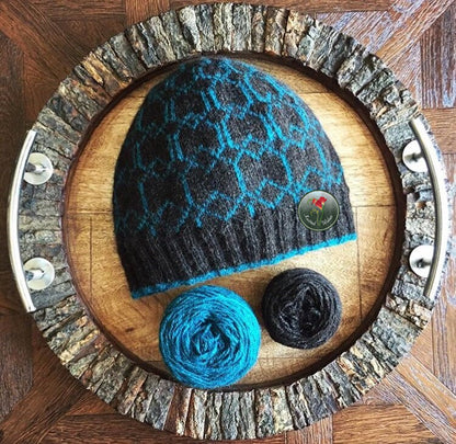 Knitted colorwork hat with blue pattern and yarn balls on a wooden tray