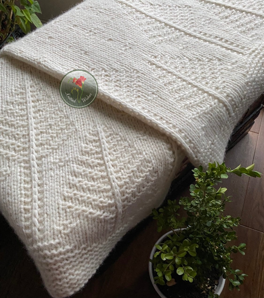 White textured tree blanket draped over a surface with a plant in the foreground