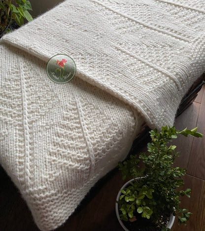 White textured tree blanket draped over a surface with a plant in the foreground