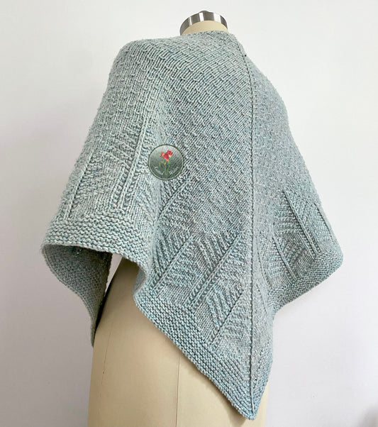 Knitted light blue shawl with a tree pattern on a mannequin against a white background