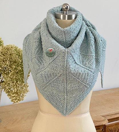 Knitted shawl with a tree pattern on a mannequin against a neutral background
