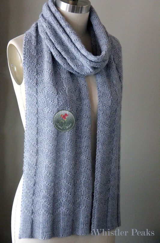 Blue textured knitted scarf against a gray background.