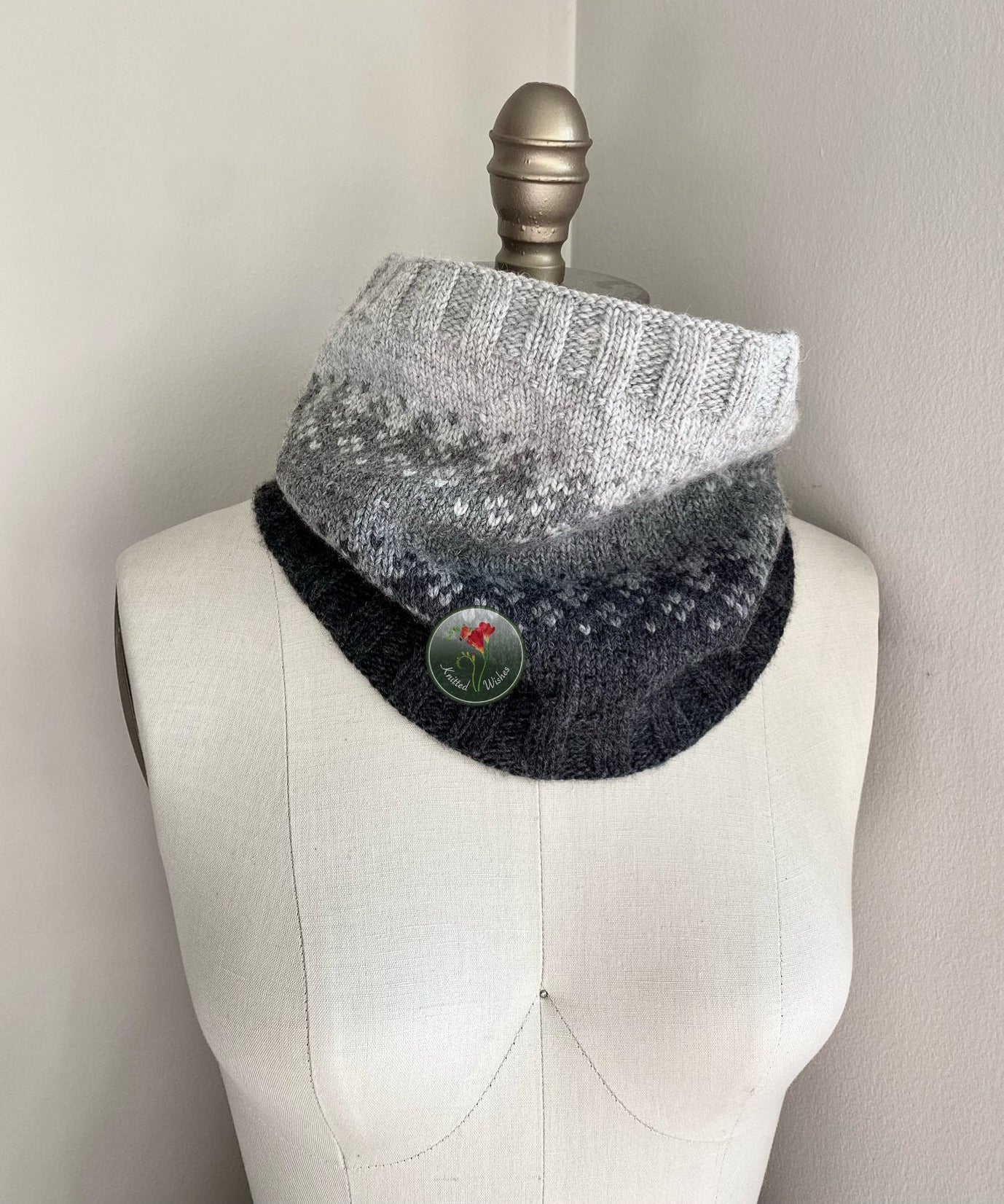 Knitted colorwork cowl with gradient design on a mannequin against a neutral background